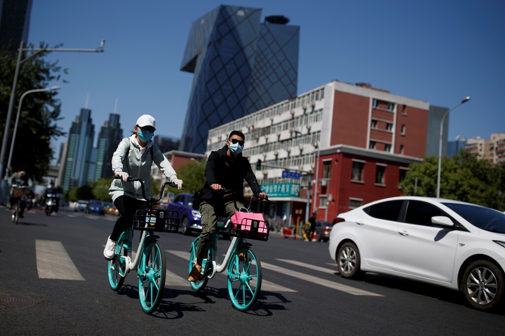 People wearing protective masks ride bikes in the Central Business District on a âblue sky day" in Beijing, as the spread of the novel coronavirus disease (COVID-19) continues, in China April 22, 2020. REUTERS/Thomas Peter - RC2M9G97ENBP