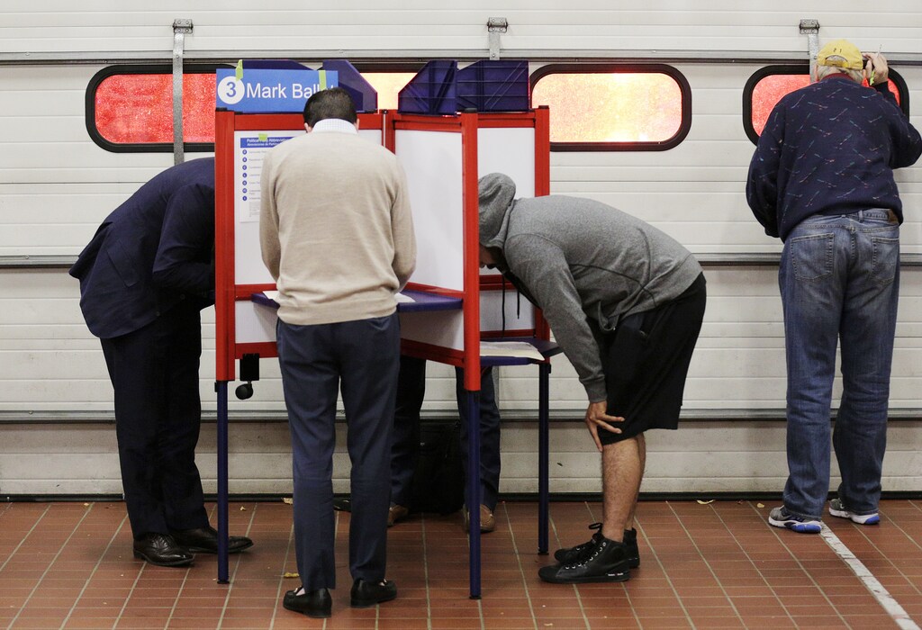 Voters look over their ballots at a fire station while a crew leaves on an emergency call during the U.S. presidential election in Arlington, Virginia, U.S., November 8, 2016. REUTERS/Joshua Roberts - HT1ECB900D0DE
