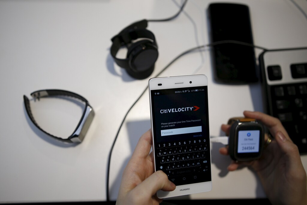 An employee holds a mobile phone and a smart watch as she works at Citi's tech hub in Tel Aviv, Israel December 14, 2015.