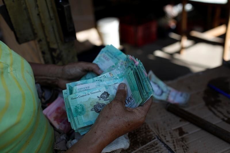 A woman counts Venezuelan bolivar notes in her stall at Las Pulgas market in Maracaibo, Venezuela July 26, 2018.