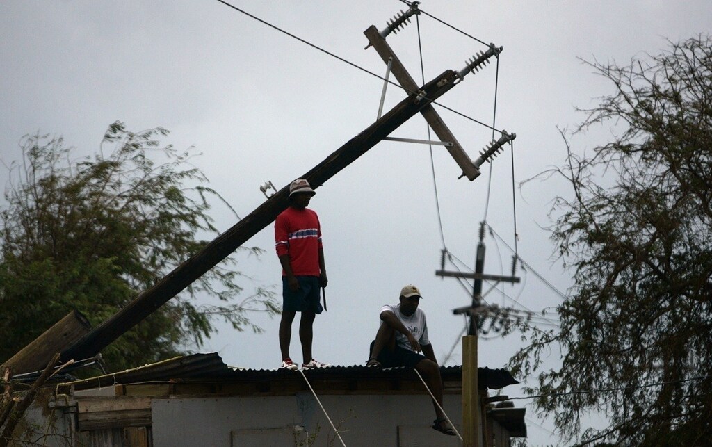 A resident of Port Royal surveys the damage after Hurricane Dean in Kingston, August 20, 2007. A strengthening Hurricane Dean took aim at Mexico's Yucatan on Monday after battering Jamaica's southern coast, flooding its capital and littering streets with broken trees and roofs during a Caribbean rampage that has killed at least nine people. Dean was an "extremely dangerous" Category 4 hurricane, the second-highest on the five-step Saffir-Simpson scale, and the U.S. National Hurricane Center said it could strengthen to a potentially catastrophic Category 5. REUTERS/Carlos Barria (JAMAICA) - GM1DVYXCYOAB