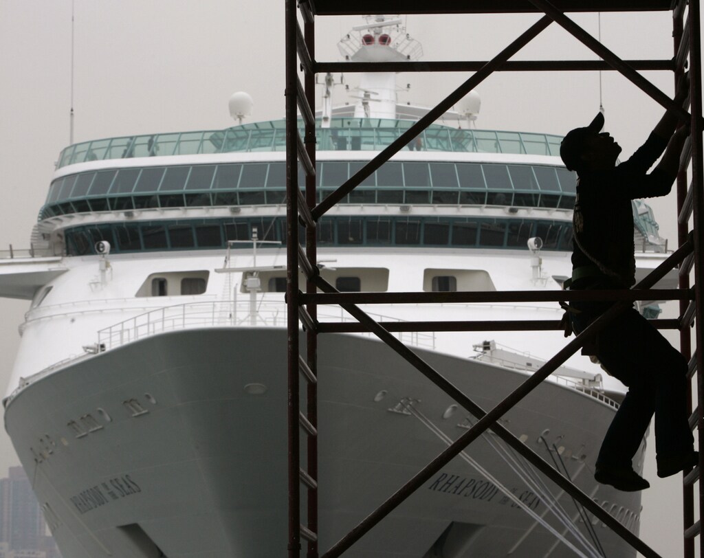 A worker climbs up a ladder in front of "Rhapsody of the Seas" at the Ocean Terminal in Hong Kong January 15, 2008. The arrival of the luxury cruise ship, owned by Royal Caribbean International, marks a new page in the development of the cruise market for Hong Kong, as well as the Asia-Pacific region, the territory's Commissioner for Tourism said on Tuesday. REUTERS/Bobby Yip (CHINA) - GM1DXAUYWBAA