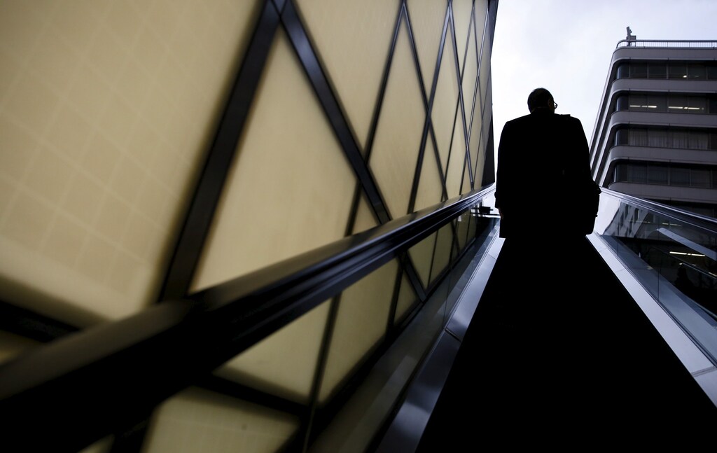 A man rides on an escalator at a building at a business district in Tokyo, Japan, February 29, 2016.