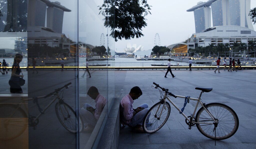 A migrant worker from India checks his mobile phone at the Marina Bay Promenade in the central business district of Singapore January 22, 2014.