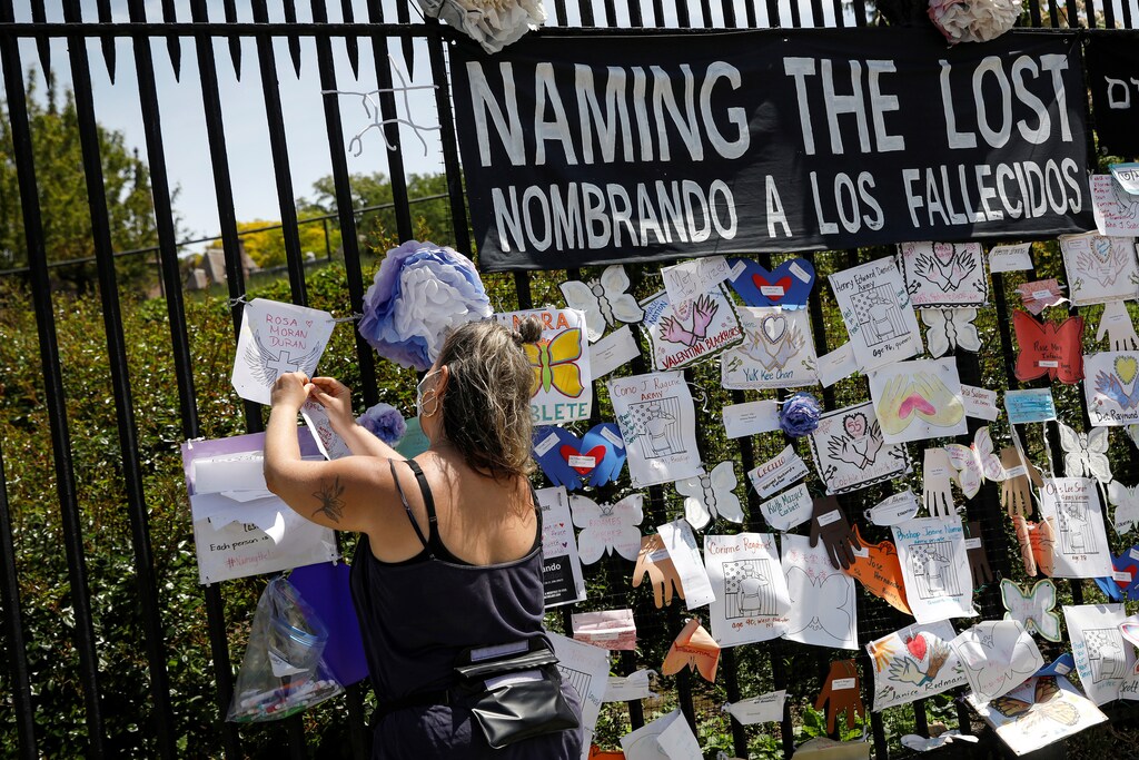 A woman adds a name on a memorial for those who have died from the coronavirus outside The Green-Wood Cemetery, during the outbreak of the coronavirus disease (COVID-19) in Brooklyn borough of New York, U.S., May 27, 2020.