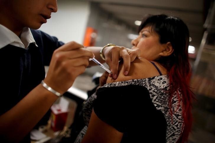 A woman receives a flu vaccination by injection for seasonal flu, after a sharp jump in cases of the virus H1N1, at a subway station in Mexico City, March 4, 2016. REUTERS/Tomas Bravo