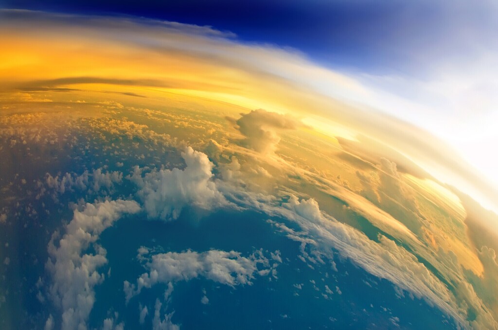 Vista aérea del planeta Tierra con el reflejo de la luz solar asomando sobrela superficie: La geoingeniería o intervención climática aspira a combatir el calentamiento global mediante intervenciones a gran escala en el sistema climático de la Tierra.