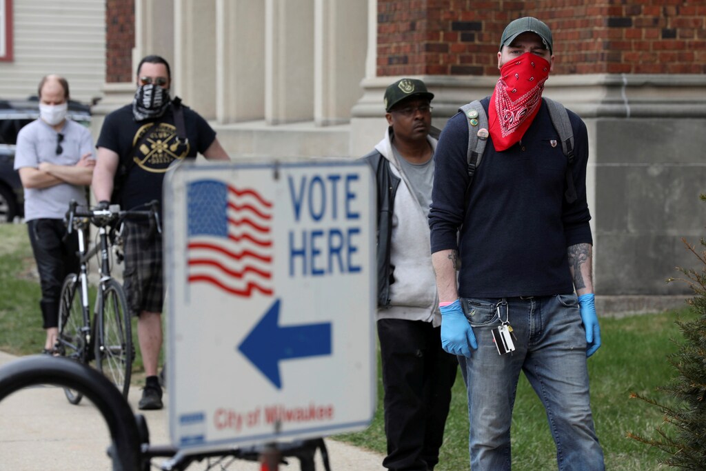 Patrick Kapple, right, waits in line outside Riverside University High School to cast a ballot during the presidential primary election held amid the coronavirus disease (COVID-19) outbreak in Milwaukee, Wisconsin, U.S. April 7, 2020. REUTERS/Daniel Acker - RC2XZF9P7TOM