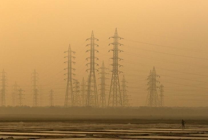 A worker levels a salt pan near electricity pylons in Mumbai, India, January 16, 2017. REUTERS/Shailesh Andrade