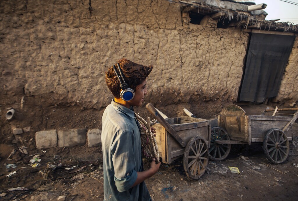 A boy listens to music while walking in a slum on the outskirts of Islamabad September 5, 2013. REUTERS/Zohra Bensemra (PAKISTAN - Tags: SOCIETY) - RTX138G4