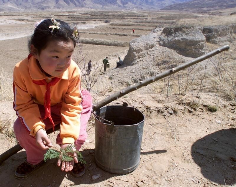 A Chinese primary student rests as she takes part in an afforestation project at Huai Lai county in Hebei province, 70kms northwest of Beijing, April 15. The environment in Huai Lai county has been deteriorating so much that patches of fields and several small mountains have been buried as a result of desertification. Official statistics show that over the past decades, desertification in the country has been deteriorating instead of improving and more than 40 per cent of China's territory had been turned into desert. Before the 1980s, China's desertified land expanded at an average rate of 1,560 square kilometers a year. The figure rose to 2,100 square kilometers a year in the 1980s and to 2,460 square kilometers in 1994. Sandstorms that swept much of northern and eastern China in the past weeks have set off alarm of deteriorating ecology in the areas. - PBEAHULLGEF