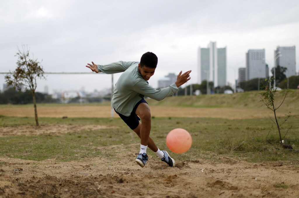 A boy plays soccer in a park in Porto Alegre June 16, 2014. In a project called 'On The Sidelines' Reuters photographers share pictures showing their own quirky and creative view of the 2014 World Cup in Brazil. REUTERS/Marko Djurica (BRAZIL - Tags: SPORT SOCCER WORLD CUP SOCIETY) - RTR3U5LF