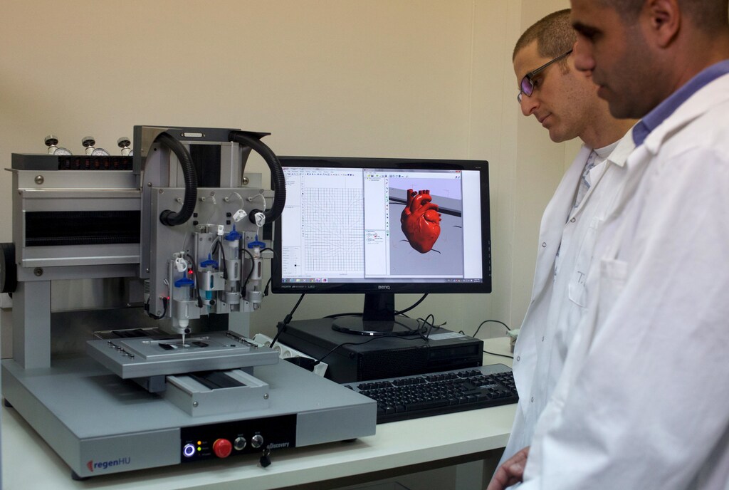 Professor Tal Dvir (R) and a researcher stand next to a 3-D printer during their interview with Reuters about their development of a 3D printed patch comprised of lab-grown heart tissue and nano-electronics that could potentially revolutionize the treatment of heart disease, at a laboratory in Tel Aviv University March 16, 2016. Picture taken March 16, 2016. REUTERS/ Nir Elias - GF10000365485