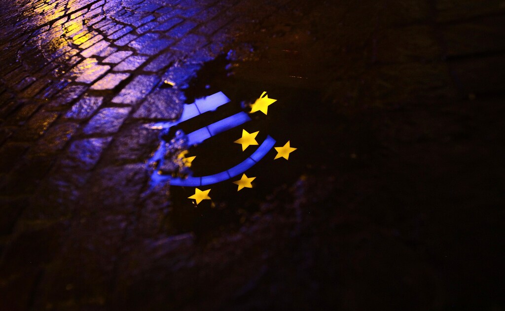 The Euro sculpture is partially reflected in a puddle on a cobblestone pavement in front of the headquarters of the European Central Bank (ECB) in Frankfurt January 21, 2012. REUTERS/Kai Pfaffenbach (POLITICS BUSINESS) - RTR2WMND