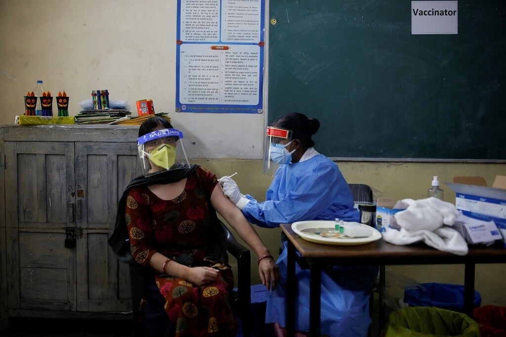 A healthcare worker gives a dose of COVISHIELD, a coronavirus disease (COVID-19) vaccine manufactured by Serum Institute of India, to a woman inside a classroom of a school, which has been converted into a temporary vaccination centre, in New Delhi, India, May 4, 2021. REUTERS/Adnan Abidi TPX IMAGES OF THE DAY - RC2S8N9W7B1K