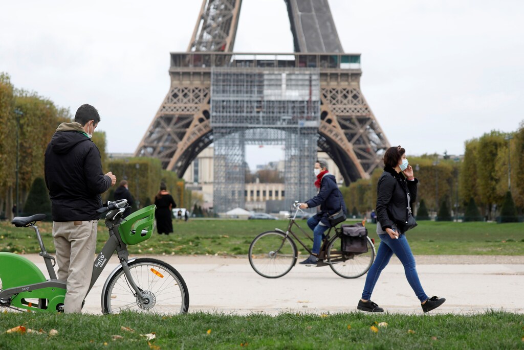 People pass by the Eiffel Tower before the national lockdown introduced as part of the new COVID-19 measures to fight a second wave of the coronavirus disease, in Paris, France, October 29, 2020. REUTERS/Charles Platiau - RC2ESJ9E8LAO
