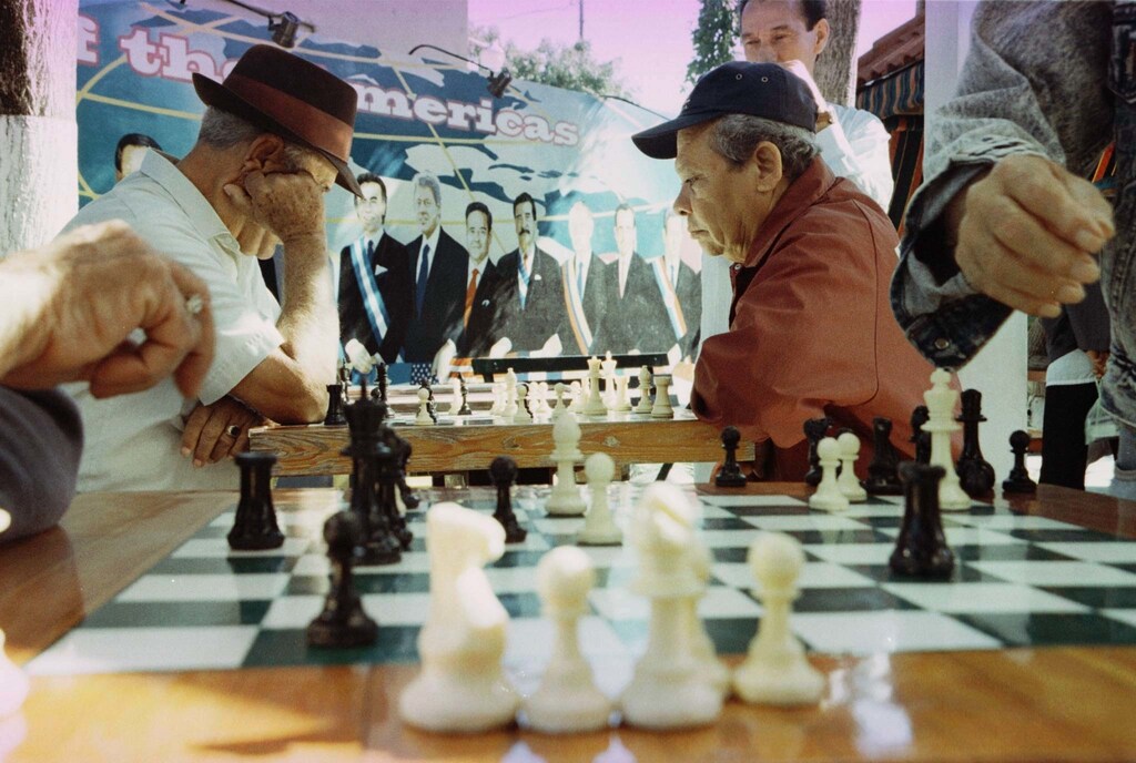 With a mural of Caribbean leaders behind them, Juan Calderon, 78, (L) and Victor Sanchez, 66, (R) spend a relaxing afternoon playing chess in Miami's Little Havana. Forty years after the revolution that brought Fidel Castro to power, an aging exile population is beginning to take a back seat to a new generation of Cuban-Americans, who regard the U.S. as home.CB/LJM - RP1DRIFQDVAE