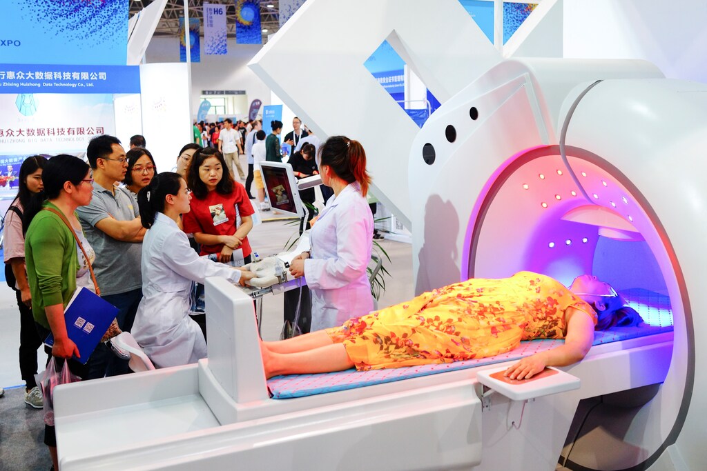 People watch a presentation of a piece of medical equipment at the China International Big Data Industry Expo in Guiyang, Guizhou province, China May 26, 2018. Picture taken May 26, 2018. REUTERS/Stringer ATTENTION EDITORS - THIS IMAGE WAS PROVIDED BY A THIRD PARTY. CHINA OUT. - RC14056FD100