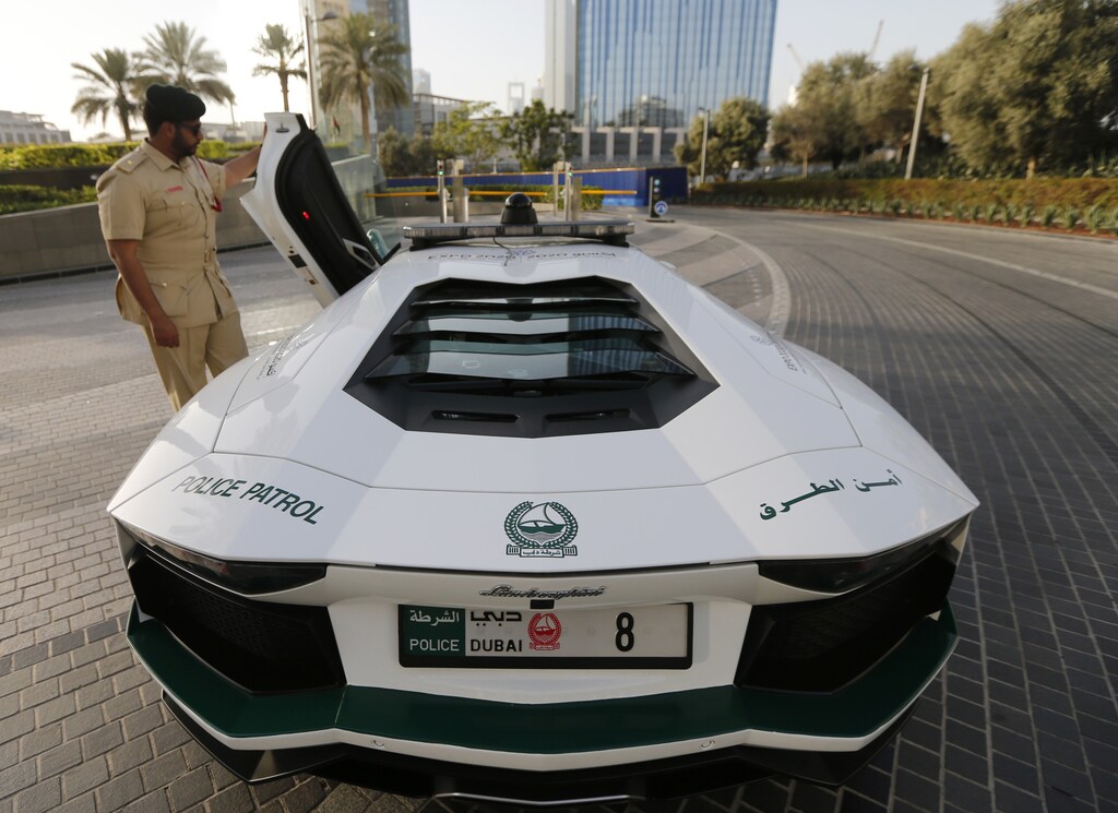 Police officer and second lieutenant Khalifa Abdullah Al-Falasi opens the door of a Lamborghini Aventador, near the Burj Khalifa in Dubai, June 4, 2013. The Dubai Police fleet of cars includes Aston Martin, Bentley Continental GT Coupe, Ferrari, and a recently added Bugatti Veyron. REUTERS/Jumana El Heloueh (UNITED ARAB EMIRATES - Tags: TRANSPORT SPORT MOTORSPORT CRIME LAW) - RTX10BOI