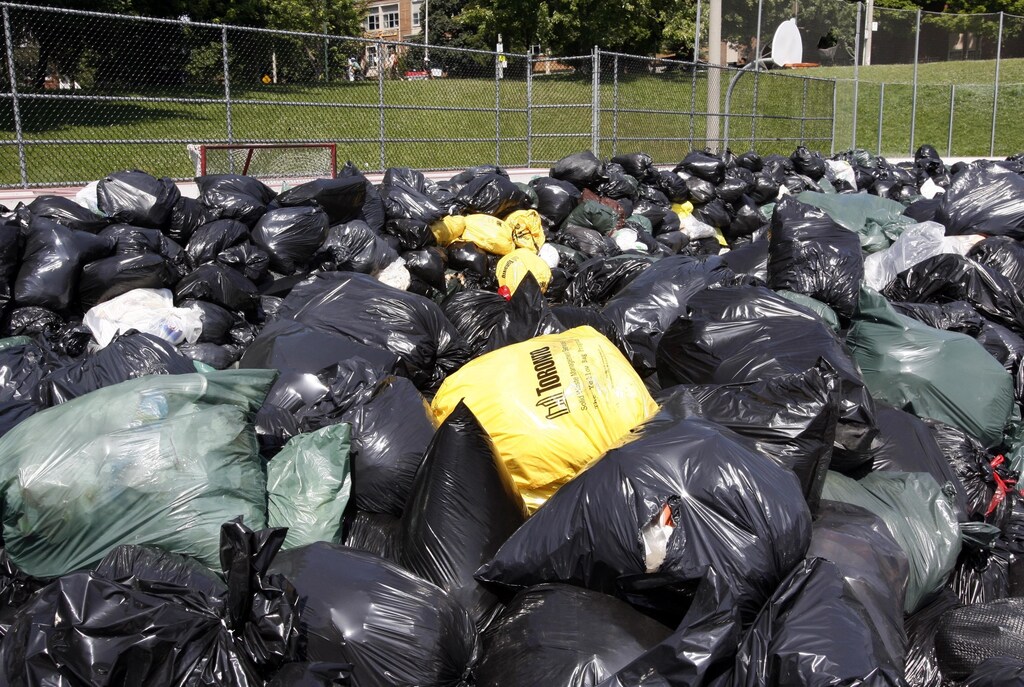 Garbage collected from residents is seen piled up at the Christie Pits Park outdoor hockey rink temporary garbage dumpsite in Toronto June 29, 2009. Nineteen temporary dump sites are up and running in Toronto for residents to get rid of perishable garbage that has been piling up at their homes during the city's week-old municipal strike by some 24,000 City of Toronto indoor and outdoor workers. REUTERS/ Mike Cassese (CANADA ENVIRONMENT EMPLOYMENT BUSINESS) - GM1E56U059E01