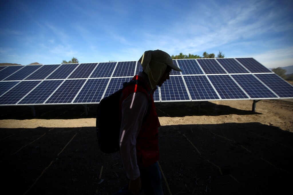 A worker walks past solar panels at a solar plant near Santiago, Chile May 5, 2017. Picture taken May 5, 2017. REUTERS/Ivan Alvarado - RC1D3E2E4110