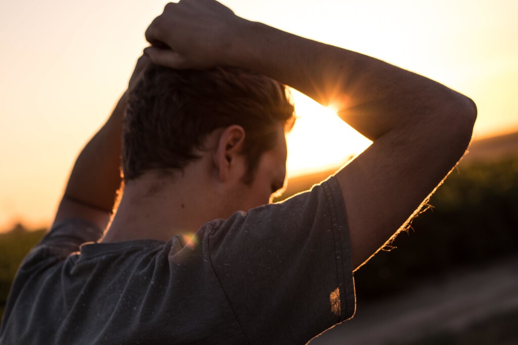A person frustrated with their hands on their head, at sunset