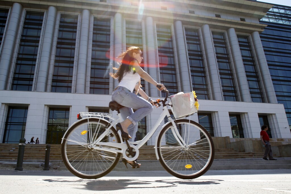 A woman rides her bicycle past Romania's National Library during its official opening ceremony in Bucharest April 23, 2012. Opened in a refurbished communist era building, Romania's National Library has a fund of more than 12 million books. REUTERS/Bogdan Cristel (ROMANIA - Tags: SOCIETY EDUCATION TRANSPORT) - GM1E84N1P3L01