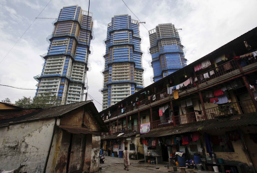 High-rise residential towers under construction are pictured behind an old residential building in central Mumbai September 9, 2011. REUTERS/Vivek Prakash