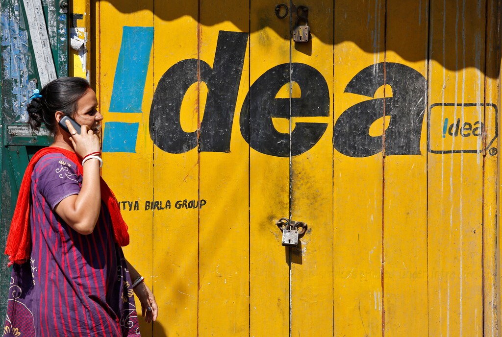 A woman speaks on her mobile phone as she walks past a shop displaying the Idea Cellular Ltd's logo on its shutter in Kolkata, India, November 13, 2017. REUTERS/Rupak De Chowdhuri - RC12D4B825A0