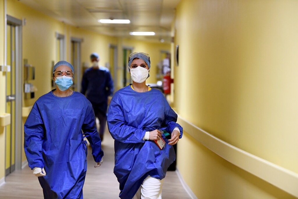 Members of the medical staff in protective suits walk along a corridor in the COVID-19 intensive care unit at the San Raffaele hospital in Milan, Italy, March 27, 2020. REUTERS/Flavio Lo Scalzo - RC2ESF9PA98G