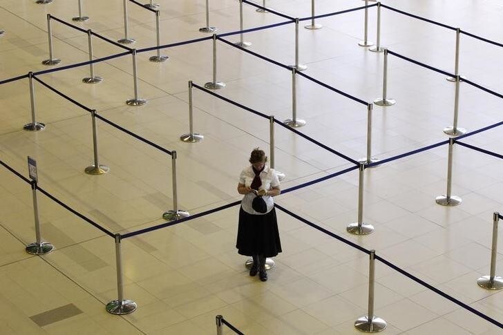 A woman reads her book at the check-in lines of a Johannesburg-bound Qantas flight at Perth international airport October 30, 2011. Tens of thousands of stranded Qantas Airways passengers are pinning their hopes on a government-appointed tribunal on Sunday ordering an end to the industrial action that grounded the Australian national carrier's entire fleet. REUTERS/Daniel Munoz (AUSTRALIA - Tags: TRANSPORT BUSINESS EMPLOYMENT CIVIL UNREST TPX IMAGES OF THE DAY)
