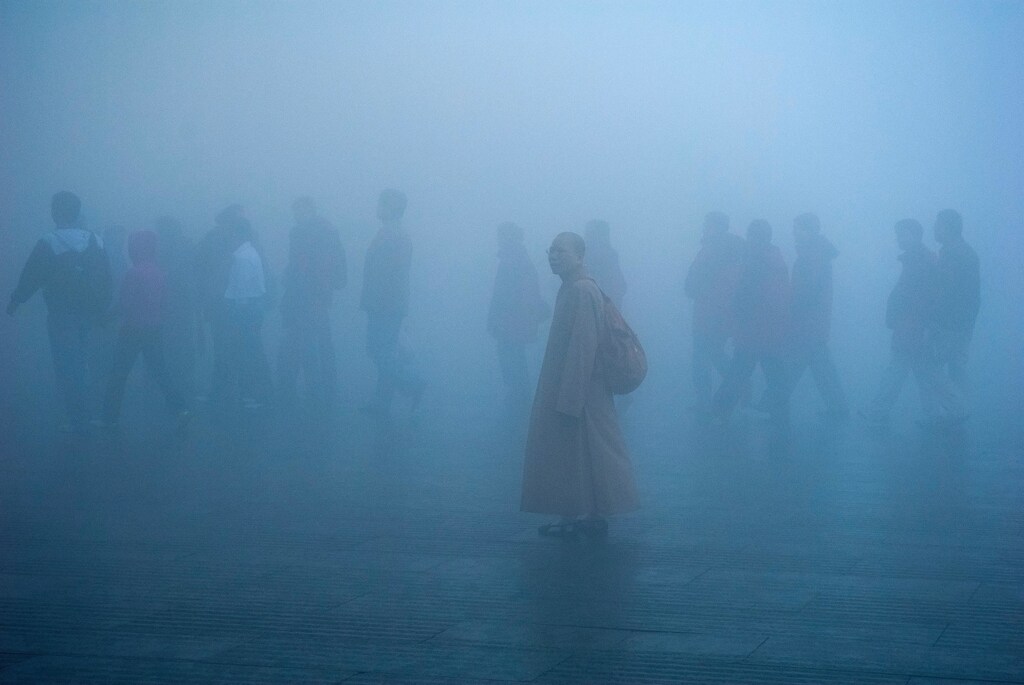 A crowd of people walking through smog.