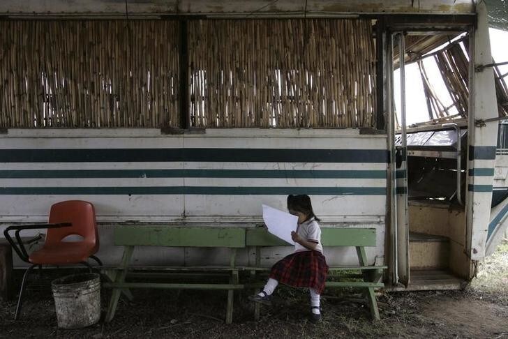 A girl from the "Insurgentes de la Paz" (Peace Insurgents) school reads outside an old bus turned into a classroom in the settlement of Pueblo Nuevo, Oaxaca September 1, 2009. The bus was donated to the neighborhood by a truck company after the other classrooms became too small for the 83 children at the school. Mexico, ridden with organized crime and drug gang violence, ranks poorly in education standards, which is holding back the country's economic growth and development according to analysts. Picture taken September 1, 2009. REUTERS/Jorge Luis Plata (MEXICO POLITICS EDUCATION SOCIETY IMAGES OF THE DAY)