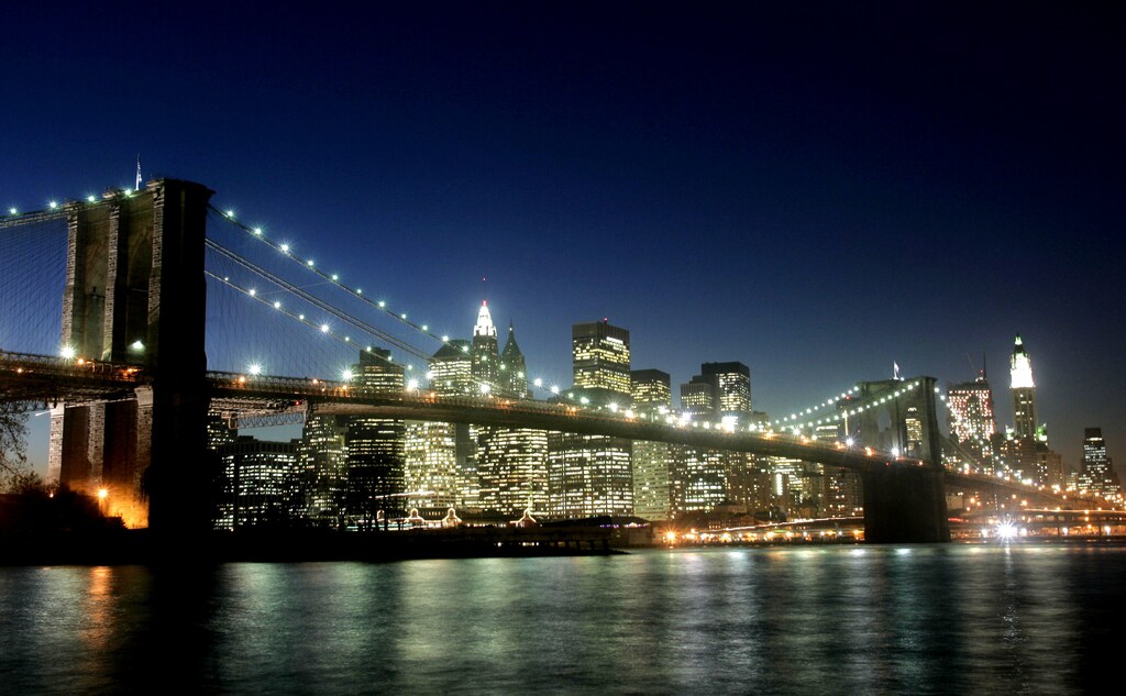 Lights from the Brooklyn Bridge and lower Manhattan skyline are reflected in the East River after sundown on November 17, 2004. REUTERS/Peter Morgan PM - RP5DRHXXMYAC