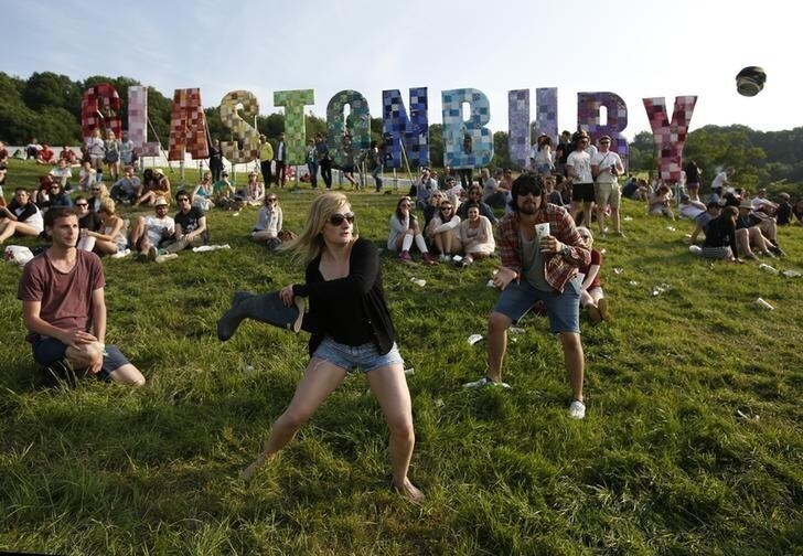 Festival goers play baseball, batting a beer can with a wellington boot, on the first day of Glastonbury music festival at Worthy Farm in Somerset, June 27, 2013. REUTERS/Olivia Harris (BRITAIN)