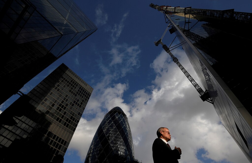 A worker walks past office skyscrapers in the City of London financial district, London, Britain, January 25, 2018. Picture taken January 25, 2018. REUTERS/Toby Melville TPX IMAGES OF THE DAY