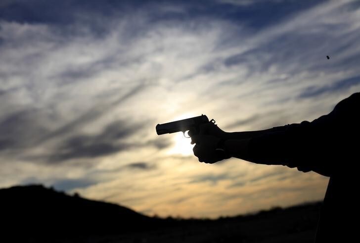 A man fires his handgun along a mountain range in Buckeye, Arizona January 20, 2013. REUTERS/Joshua Lott (UNITED STATES - Tags: SOCIETY)