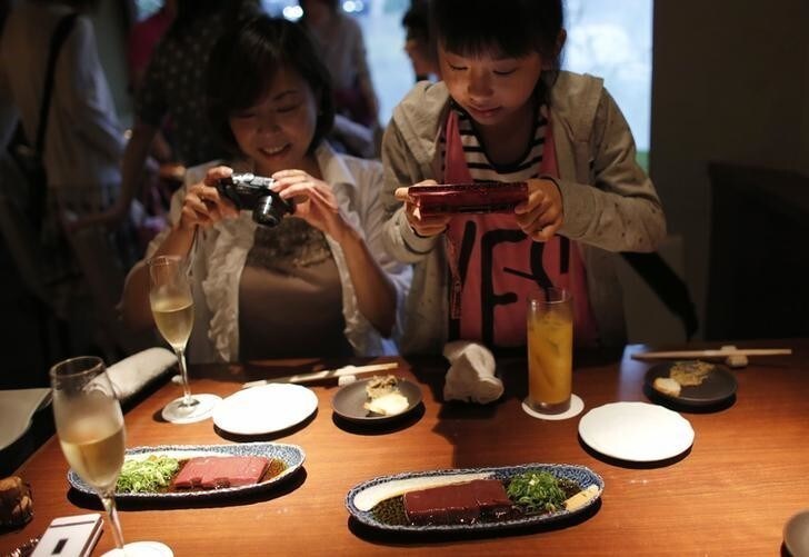 Yurika Miki (R) and her mother Yoshiko take photos of raw beef liver sashimi before eating them at a restaurant in Tokyo June 28, 2012. While Japan has a reputation as the home of sushi and sashimi, one item is about to be taken off the menu as Japan's government looks to ban the popular dish of raw liver in sashimi style. The dish, which consists of raw beef liver sliced up into bite sized chunks and then served with onions and sauce had become a popular dish across the country. Picture taken June 28, 2012. REUTERS/Toru Hanai (JAPAN - Tags: BUSINESS FOOD SOCIETY)