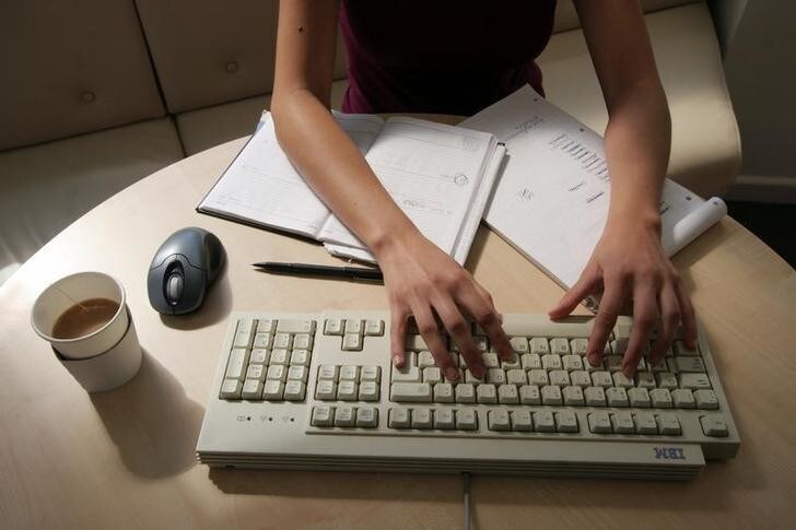 A generic picture of a woman working in an office sitting at her desk typing on a computer. REUTERS/Catherine Benson CRB