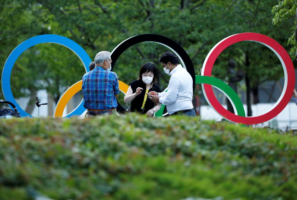People chat next to Olympic Rings monument outside the Japan Olympic Committee (JOC) headquarters near the National Stadium, the main stadium for the 2020 Tokyo Olympic Games that have been postponed to 2021 due to the COVID-19 pandemic, in Tokyo, June 23, 2021 on the day to mark one month to go until the opening of the Olympic Games. REUTERS/Issei Kato - RC296O9SBN01