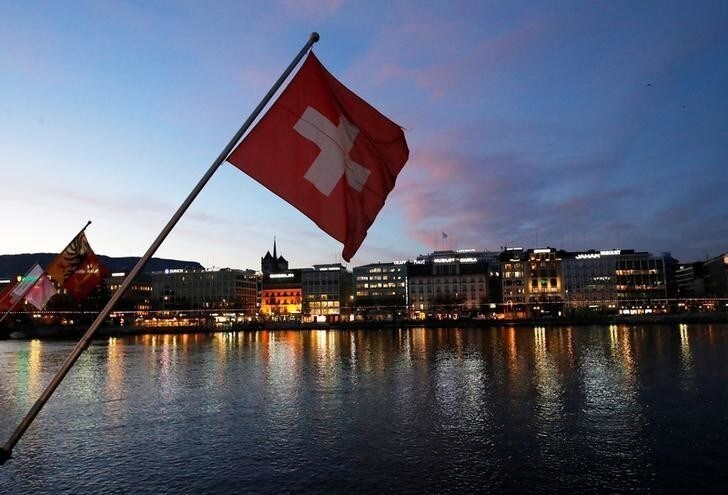 A Swiss flag is pictured during the sunrise on the Commercial and Financial District in Geneva, Switzerland, November 23, 2017. REUTERS/Denis Balibouse