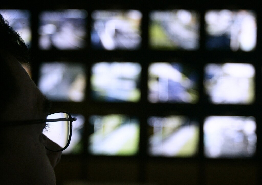 A surveillance monitoring expert watches a bank of screens showing images from Edinburgh City Council's network of CCTV cameras in Edinburgh, Scotland November 2, 2006. Britain is becoming a surveillance society where individuals are filmed hundreds of times a day by security cameras and where firms "data mine" to build customer profiles, its information commissioner said on Thursday. REUTERS/David Moir (BRITAIN) - RTR1IXMS