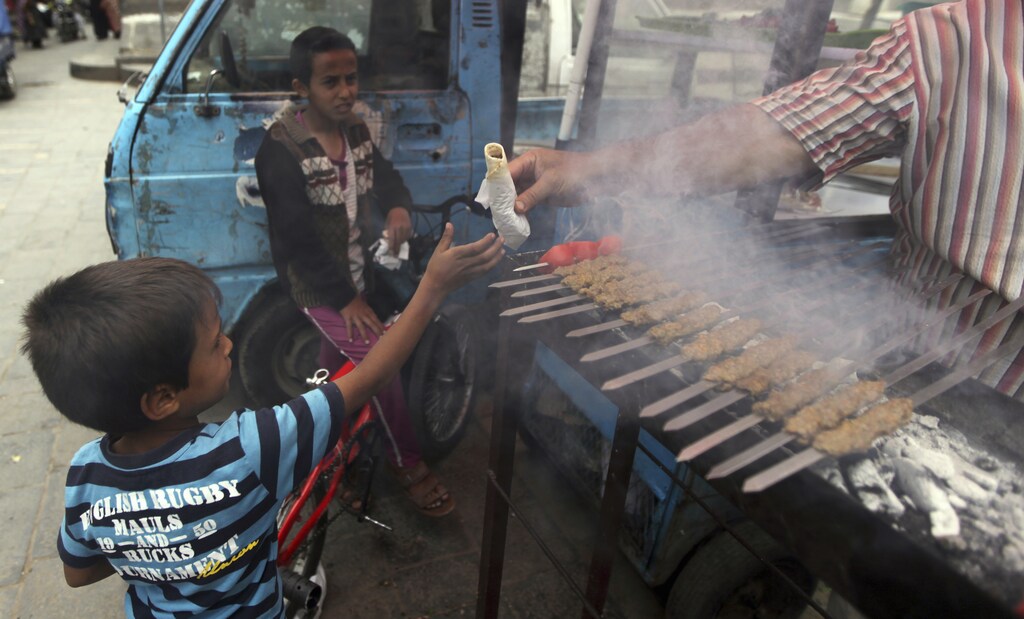 A child takes a sandwich from a kebab street vendor in Sanaa July 3, 2013. According to the United Nations, there are approximately five million people in Yemen who are either suffering from food insecurity or are at risk of acute food insecurity caused by rising food and fuel prices and political instability. REUTERS/Mohamed al-Sayaghi (YEMEN - Tags: FOOD SOCIETY BUSINESS) - GM1E97401PY01