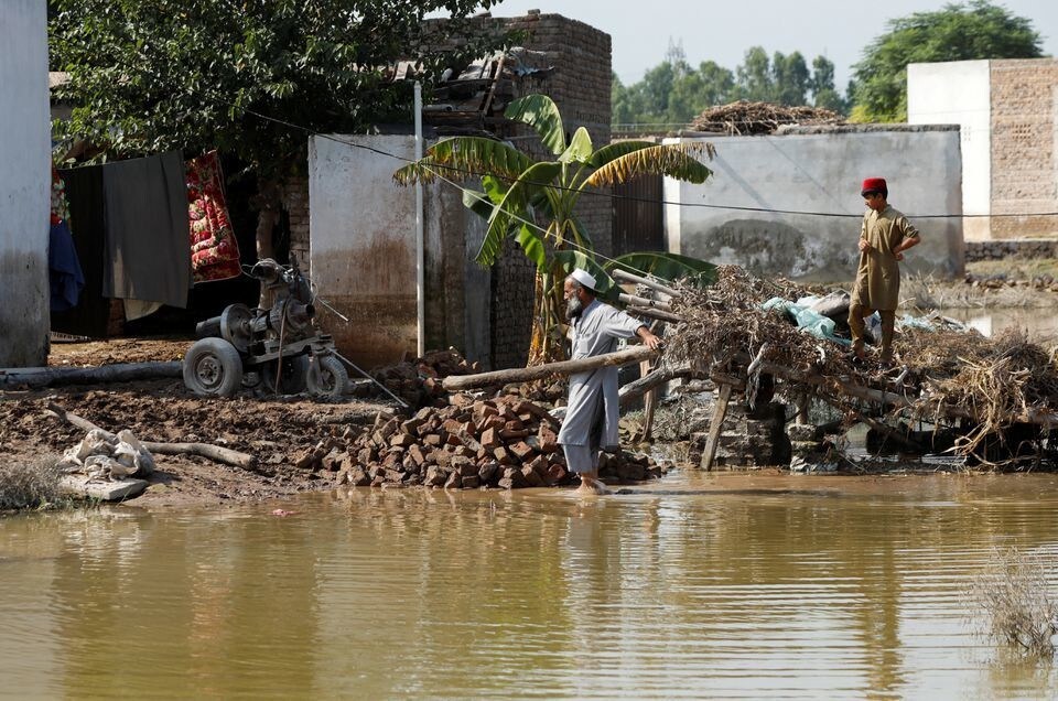 A man clears rubble of his makeshift stall amid flood water, following rains and floods during the monsoon season in Nowshera, Pakistan