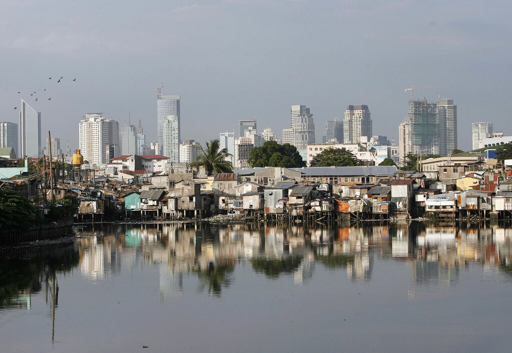 Slums are seen along a river with the skyline of Makati, Manila's financial district, in the background October 8, 2007. Developing countries in Asia are struggling to meet the UN-set millennium goals although the region is on course to cut extreme poverty, a report released on Monday showed. REUTERS/Cheryl Ravelo (PHILIPPINES) - GM1DWICSWHAA