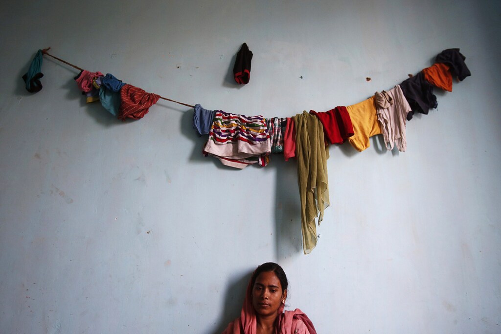 Sania, 25, sits underneath a line of clothes hung up to dry in the living room of their flat in an illegal building located next to the site of a building which collapsed last week, in Thane district on the outskirts of Mumbai April 10, 2013. A shortage of affordable housing in Indian cities has led to rampant illegal construction by developers using cheap materials and shoddy methods in order to offer low-cost homes to low-paid workers, paying bribes to officials to turn a blind eye. Despite several promises by the government to build affordable homes for India's poor in densely populated cities, the country's urban housing shortage is estimated at nearly 19 million households. That lack of affordable housing is especially acute in Mumbai, India's financial capital and home to some of the world's costliest real estate, where an estimated six out of every 10 people live in slums. Picture taken April 10, 2013. REUTERS/Vivek Prakash (INDIA - Tags: SOCIETY TPX IMAGES OF THE DAY) - GM1E94C05KW01