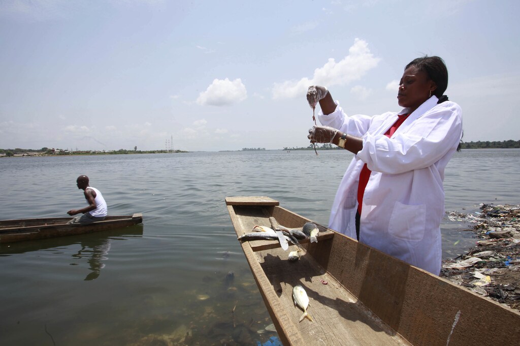 Dr. Celine Nobah (R) of the Association of Women Researchers in the Ivory Coast (AFEMC-CI) stands beside a canoe as she conducts research to ensure that fish in the lagoon Ebrie are safe for consumption, in Nbadon, Abidjan March 4, 2013. The association was formed to raise the profile of women working in scientific research in the Ivory Coast. It helps women raise funding for their projects and seeks to promote scientific research, a field dominated by men, as a viable career option among young women by helping them obtain scholarships. REUTERS/Thierry Gouegnon (IVORY COAST - Tags: SCIENCE TECHNOLOGY BUSINESS MARITIME) - GM1E9370LT601