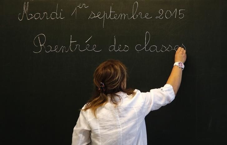 A teacher writes the phrase "Tuesday, September 1, 2015, start of the new school year" on the blackboard before the arrival of French President Francois Hollande at the Groupe Le Marais primary school in Pouilly-sur-Serre, near Laon, northern France, September 1, 2015. REUTERS/Jacky Naegelen