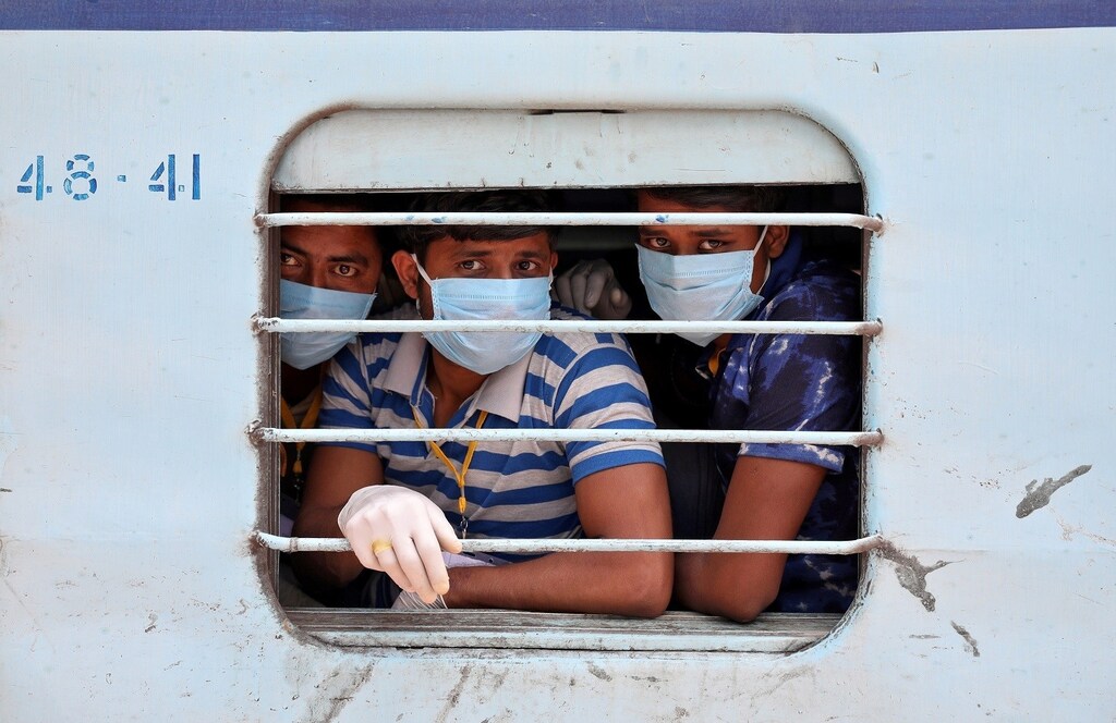 Migrant workers, who were stranded in the western state of Rajasthan due to a lockdown imposed by the government to prevent the spread of coronavirus disease (COVID-19), wear protective masks as they look out from a window of a train upon their arrival in their home state of eastern West Bengal, at a railway station on the outskirts of Kolkata, India, May 5, 2020. REUTERS/Rupak De Chowdhuri TPX IMAGES OF THE DAY - RC27IG9ICJTR