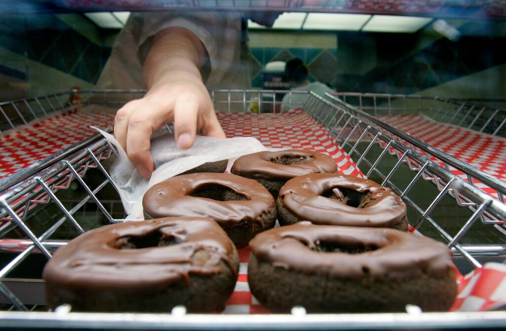 A Tim Hortons employee grabs a doughnut for a customer at the Pengrowth Saddledome in Calgary March 24, 2006. Shares of Canadian coffee and doughnut chain Tim Hortons Inc. rose about a third in their market debut on Friday, the day after the company sold $671.7 million worth of shares in its initial public offering. REUTERS/J.P. Moczulski - GM1DSFSYWAAA